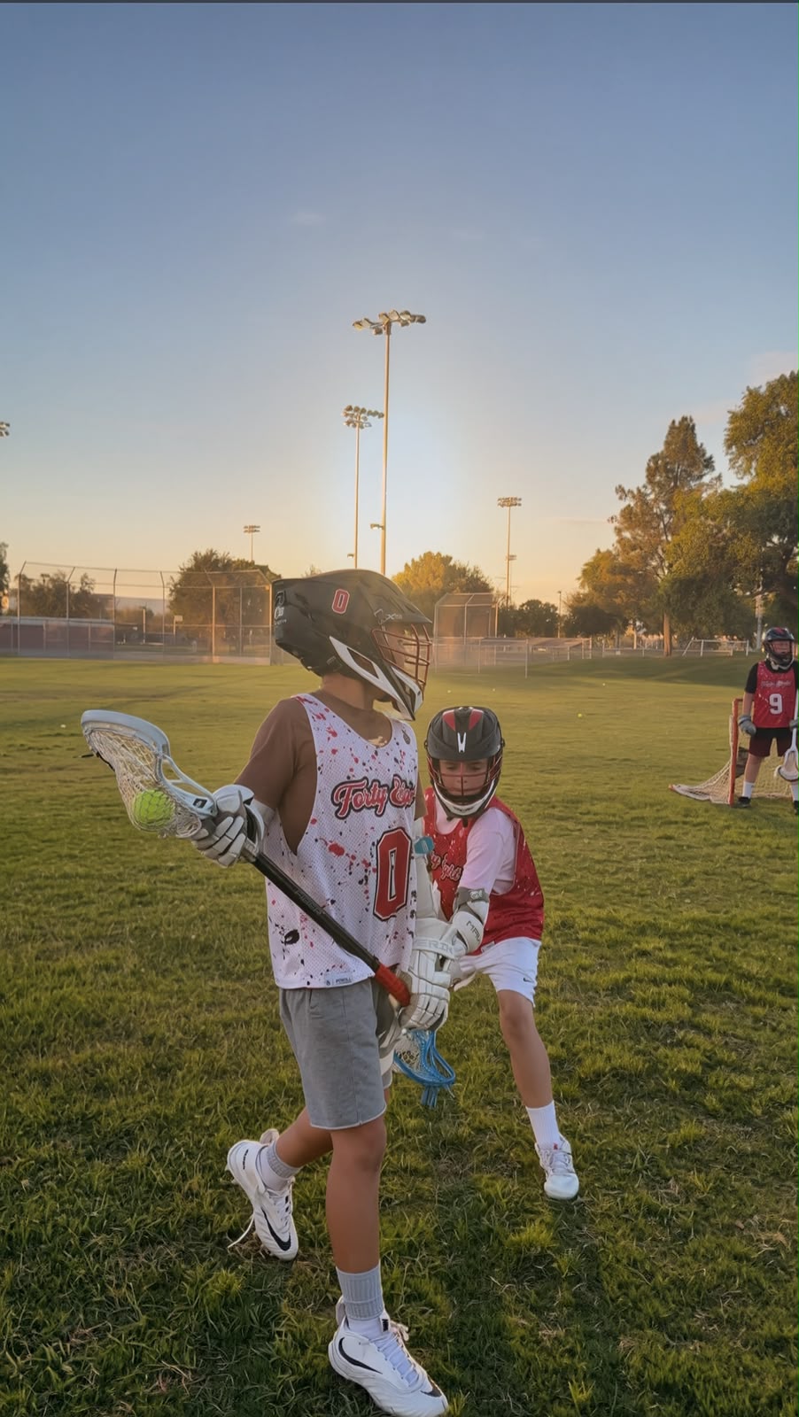 Two young lacrosse athletes competing for possession during practice