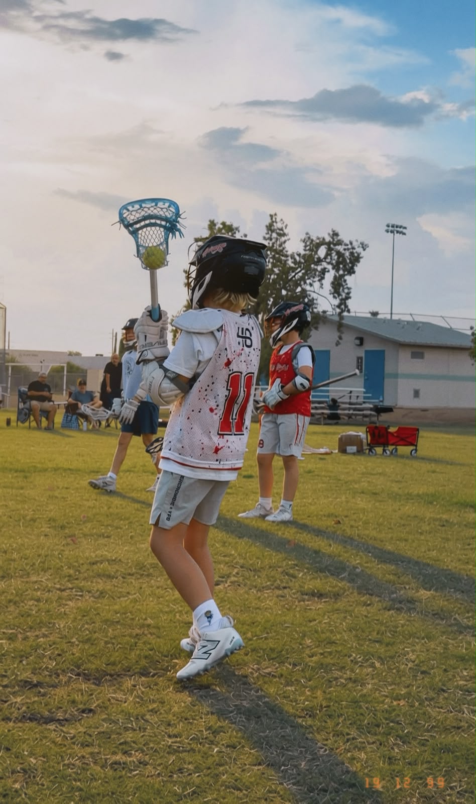A young lacrosse athlete carrying the ball during a field drill