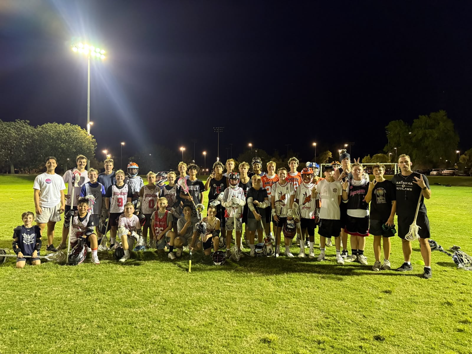 Valley Boys Lacrosse athletes and coaches posing together under the field lights